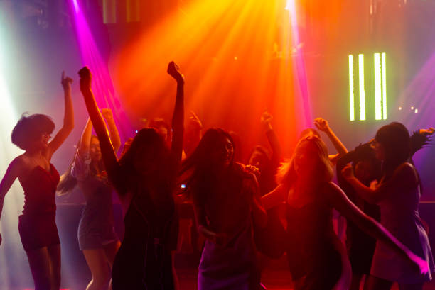 istock Silhouette image of people dance in disco night club to music from DJ on stage 1299410607