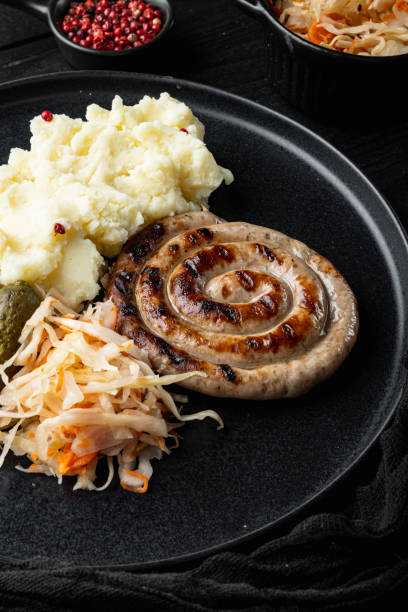 istock Rustic food with roasted sausage mashed potatoes and sour cabbage, on black wooden table background 1299410669
