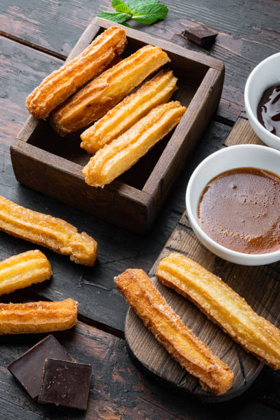 istock Typical Spanish snack  churros, fried-dough pastry served  usually with chocolate caramel hot sauce, on old dark  wooden table background 1299411738