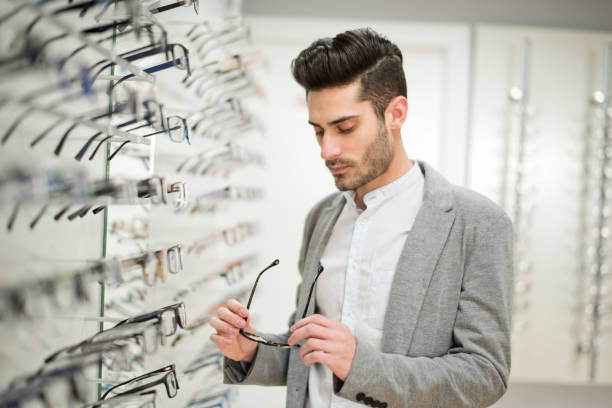 istock Man looking some glasses in optical store, trying on lenses and looking quality 1299411806