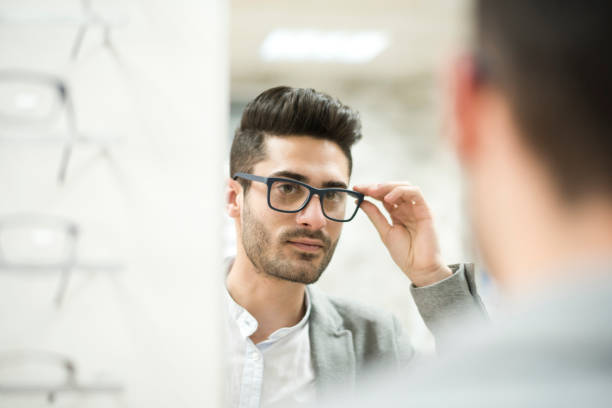 Man looking and trying on glasses in optical store.