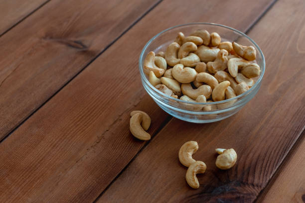 istock Bowl with roasted cashew nuts on wooden table 1299411840