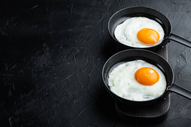 istock Fried Egg with ingredients in cast iron frying pan, on black background , with space for text  copyspace 1299412143