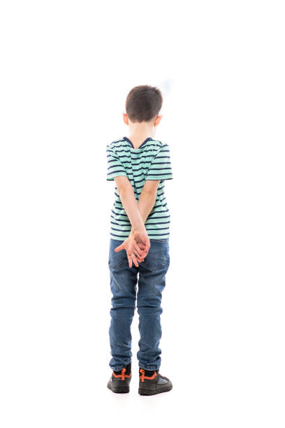 Back view of sad unhappy young boy with Easter bunny ears looking down with hands behind back Back view of sad unhappy young boy with Easter bunny ears looking down with hands behind back. Full length isolated on white background. hands behind back stock pictures, royalty-free photos & images