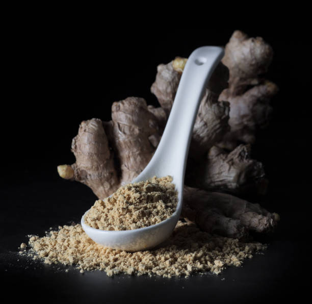 istock Ginger root and ginger powder in a spoon on black background, close-up. 1299413890