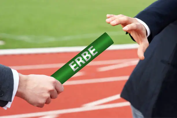 Photo of Starting the legacy - businessman passes the baton with the German word Erbe