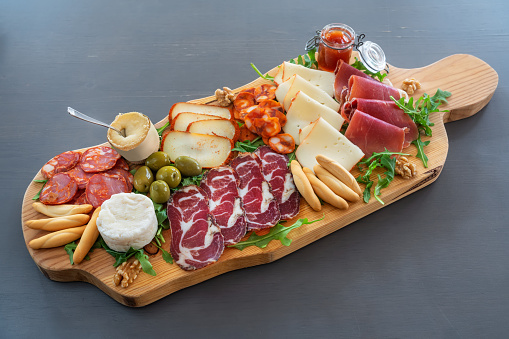 Very colorful tapas board of charcuterie with cheese and smoked meats. Decorated with arugula and walnuts. High quality photo