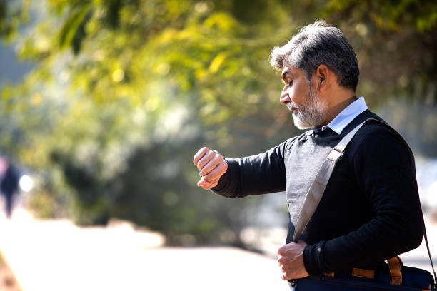 Businessman looking at wristwatch and checking time while waiting outdoors
