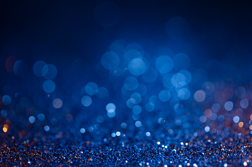 Decoration bokeh glitters background, abstract shiny backdrop with circles,modern design overlay with sparkling glimmers. Blue and golden backdrop glittering sparks with blur effect