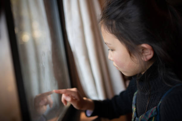 istock Girl touching the window glass 1299429669