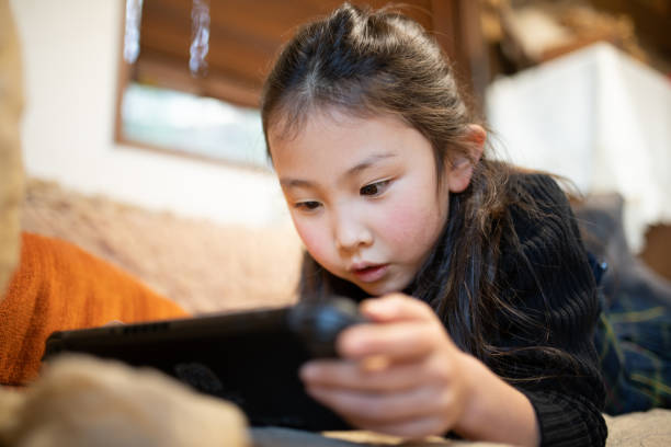 Girl playing games on the sofa Girl playing games on the sofa handheld video game stock pictures, royalty-free photos & images