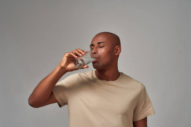 istock Multiracial person drinking water after swallowing a pill 1299433055