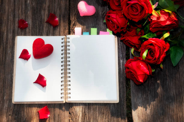 istock empty notepad  and red rose petals on wood background, top view. Valentine's day celebration 1299434275