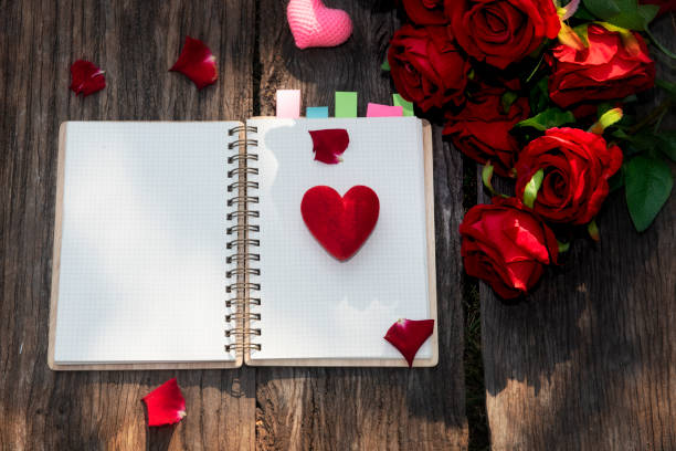 istock empty notepad  and red rose petals on wood background, top view. Valentine's day celebration 1299434284