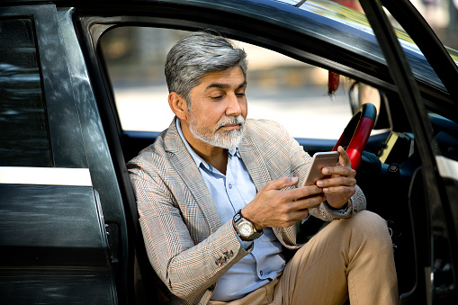 Businessman texting on mobile while sitting inside car