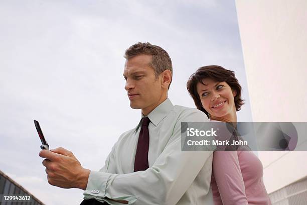 Business People Sitting Outdoors Stock Photo - Download Image Now - Back To Back, Looking Over Shoulder, Mobile Phone