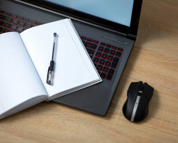 istock Laptop with wireless mouse, notebook and pen on the office table 1299436367