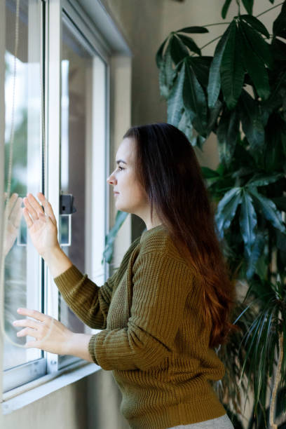 istock Mental health, stress, depression during quarantine, covid 19 coronavirus lockdown, lonely young woman looking window, negative emotions and mental health concept 1299436433