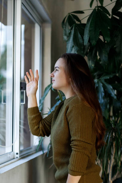 istock Mental health, stress, depression during quarantine, covid 19 coronavirus lockdown, lonely young woman looking window, negative emotions and mental health concept 1299436435