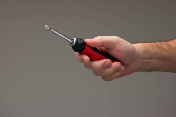 istock Caucasian male hand holding a red plastic handle screwdriver isolated on gray background 1299438128