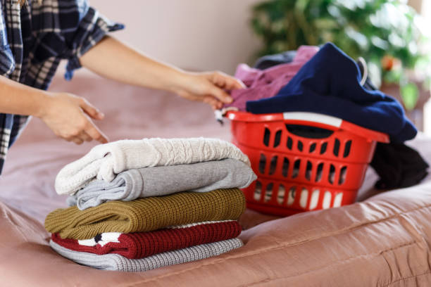 istock Woman hands folding clothes in a bedroom, taking from laundry box 1299440484