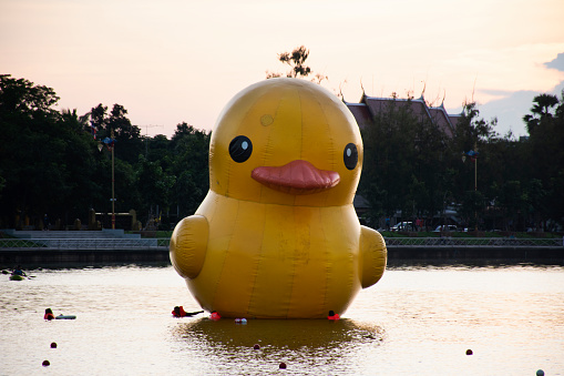 View cityscape Udonthani city and landscape and yellow duck rubber doll in pond dusk time for thai people travel visit relax at of Nong Prajak Recreation Centre Public Park in Udon Thani, Thailand