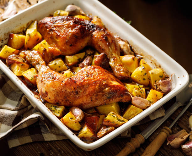 Baked chicken leg quarters  seasoned with garlic and herbs with potatoes in a baking dish on a wooden table Baked chicken leg quarters  seasoned with garlic and herbs with potatoes in a baking dish on a wooden table close up view chicken leg stock pictures, royalty-free photos & images