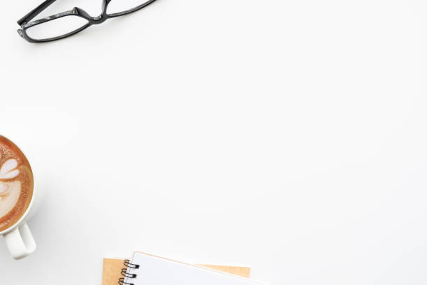 istock White office desk table with notebooks, cup of coffee and eye glasses. Top view with copy space flat lay. 1299443139
