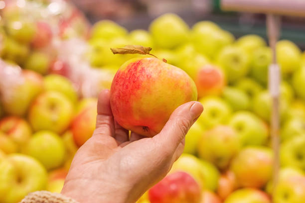 istock Supermarket. A ripe apple in a hand. 1299444191