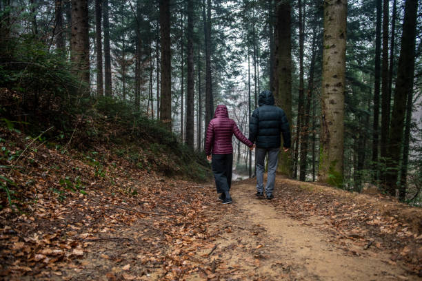 istock Couple back view hiking and holding hands into the Rainy Forest 1299444687