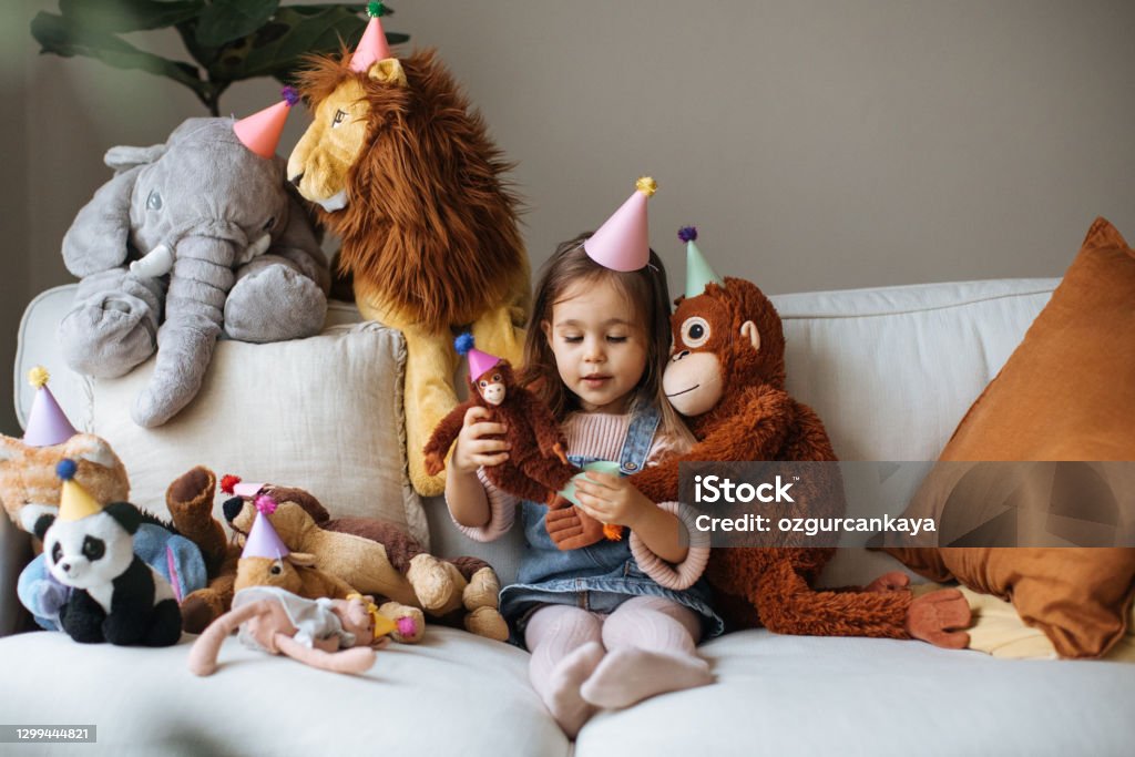 It's time for playing and I love it! Cute happy little girl embracing teddy bear. Pretty female kid at home, sitting on sofa with her favorite toy, copy space Child Stock Photo