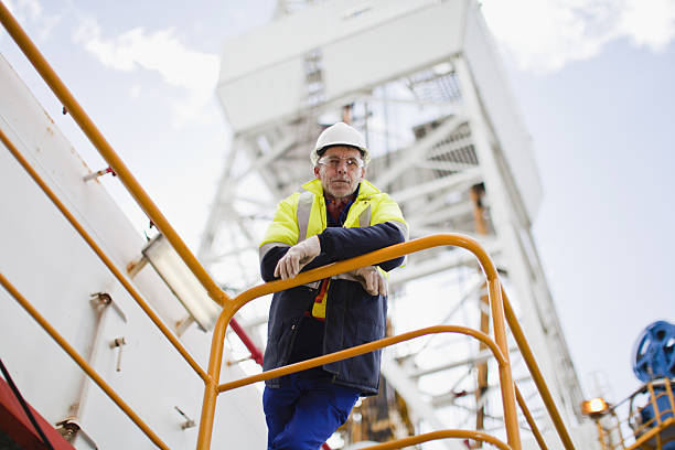 operaio appoggiato sulla ringhiera di impianto di perforazione petrolifera - working platform foto e immagini stock