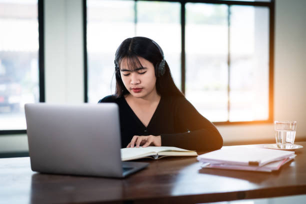 istock Teenage university student wears wireless headphones write on the notebook to study language online watch and listen to the lecturer, webinar via video call e-learning at home, distance education 1299445904