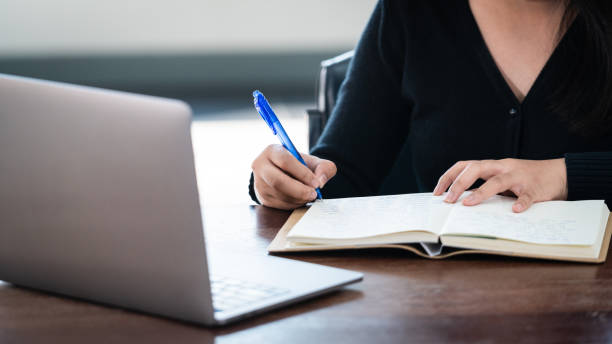 istock Teenage university student wears wireless headphones write on the notebook to study language online watch and listen to the lecturer, webinar via video call e-learning at home, distance education 1299445906