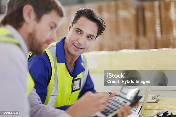 Workers Using Laptop In Warehouse Stock Photo - Download Image Now - Calculator, Industry, Men