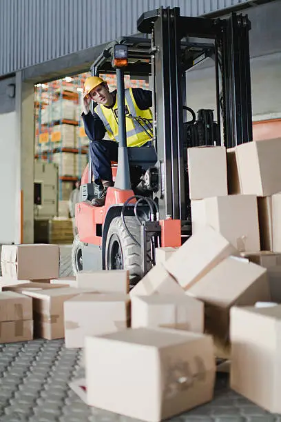 Photo of Worker using forklift to pick up boxes