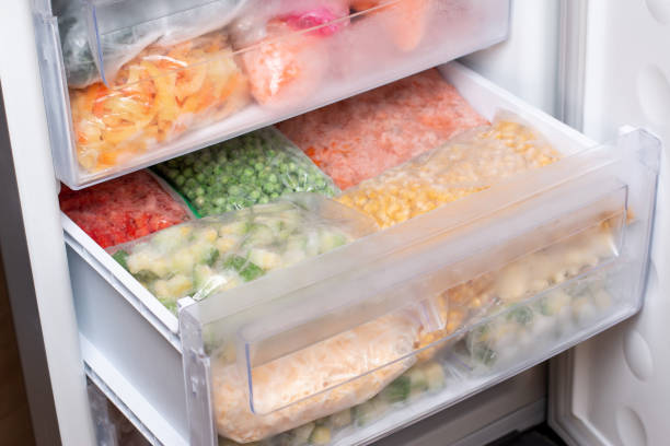 istock Plastic bags with different frozen vegetables in refrigerator. 1299446897