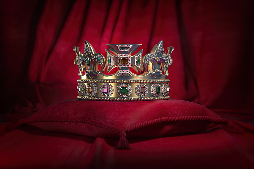 Golden crown on red velvet background Royal symbol, coronation.
