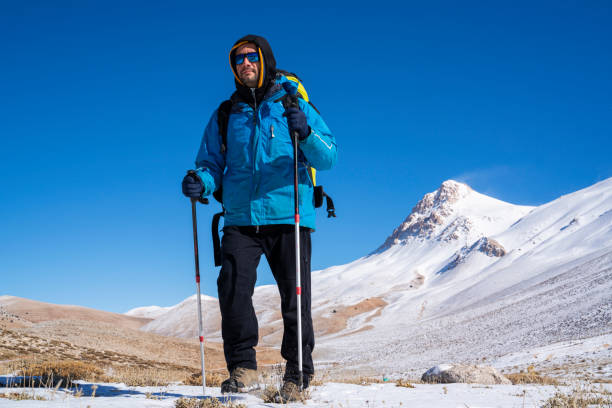 istock Man hiking on the mountains in winter with parachute backpack 1299447132