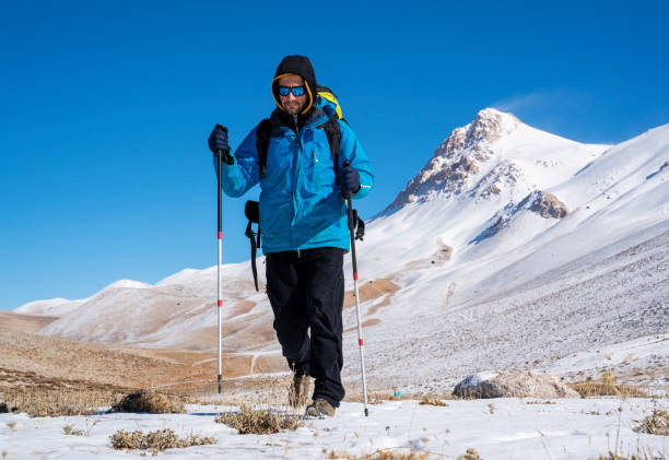 istock Man hiking on the mountains in winter with parachute backpack 1299447150
