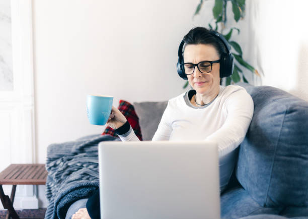 istock woman with her laptop working from her couch at home using headphones 1299447264