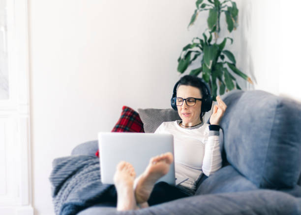 istock woman with her laptop working from her couch at home using headphones 1299447282