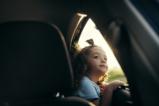 Little girl looking in the car window at sunset