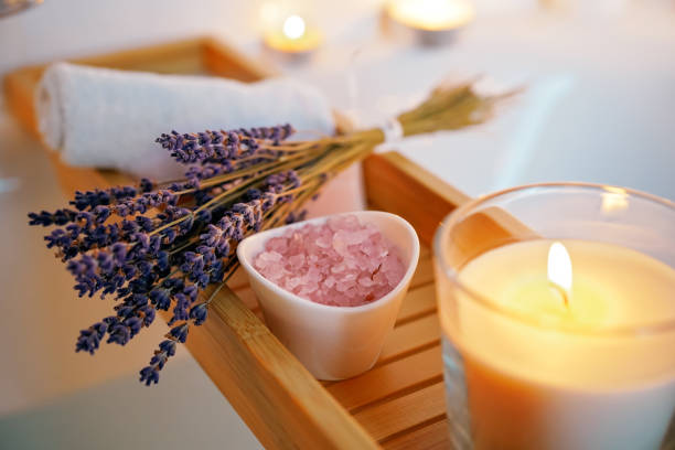 Spiritual aura cleansing ritual bath for full moon ritual. Candles, aroma salt and lavender on tub table, close up stock photo