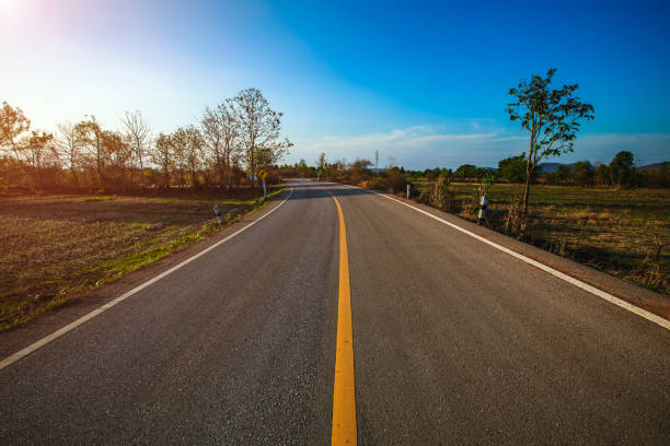 istock Empty asphalt road through the green field and clouds on blue sky in summer day. 1299450808