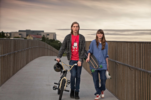 Teenagers with bicycle and skateboard