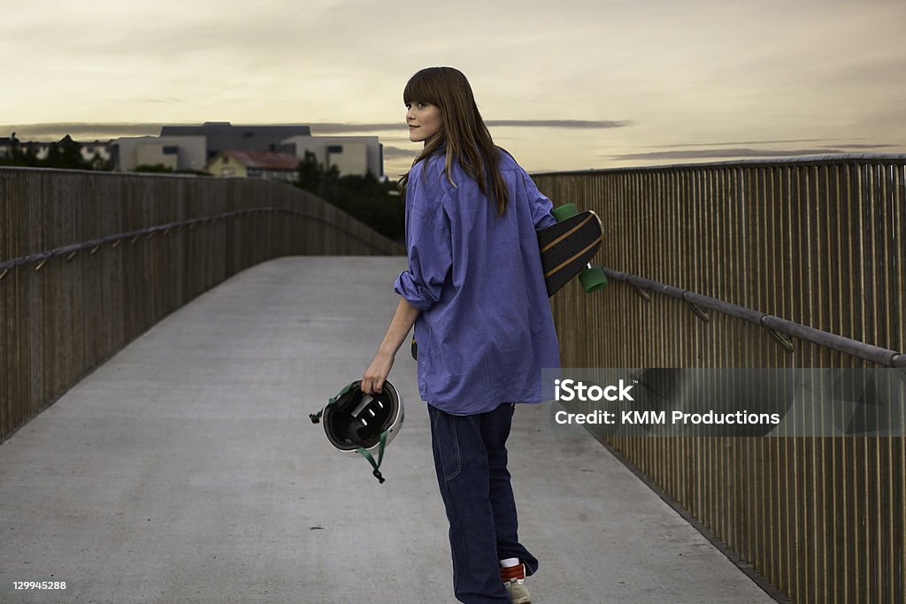 Girl carrying skateboard on walkway  14-15 Years Stock Photo