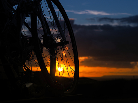 Wheels of two bikes on a bike rack with sunset behind.