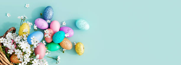 istock Bunch of colorful eggs in a basket with spring flowers on a blue Easter background 1299454331