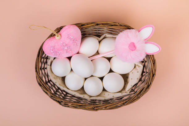 istock Easter. White eggs in a basket on a uniform pink background. Place for text. 1299454546